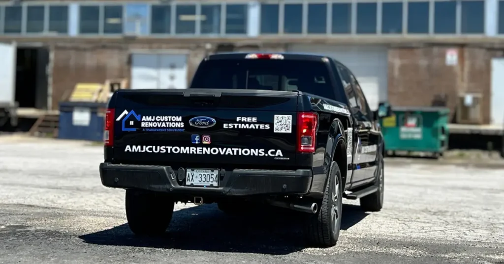 A rear view of a 2015 Ford F-150 displaying AMJ Custom Renovations decals